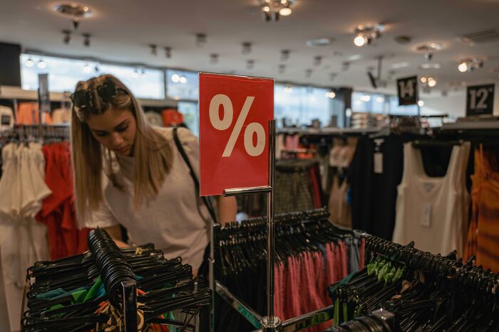 Shopper browses clothing racks with a discount sign, evoking false advertisement themes.