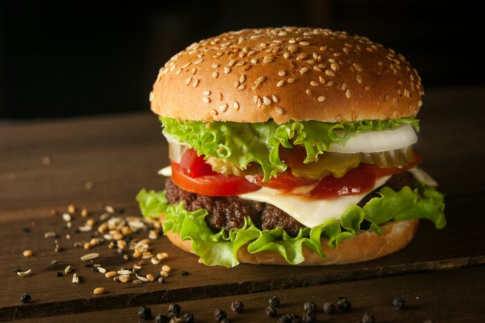 Juicy burger with fresh toppings, illustrating potential false advertisement by companies in fast food marketing.