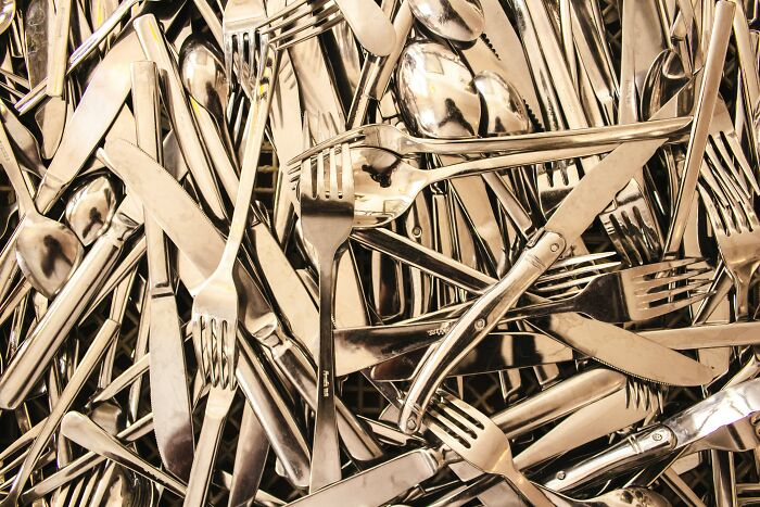 Piled silver cutlery, showcasing a chaotic collection of forks, knives, and spoons, reflecting on school weirdness.