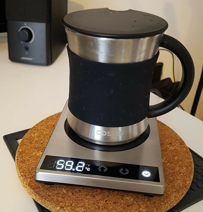 A mug on a warming plate displaying 99.8°F, illustrating how buying useful items can improve daily life.