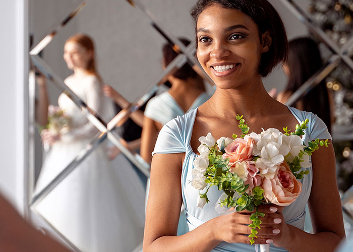 Bridesmaid holding flowers with a smiling bride in the background, related to canceled wedding cake issue.