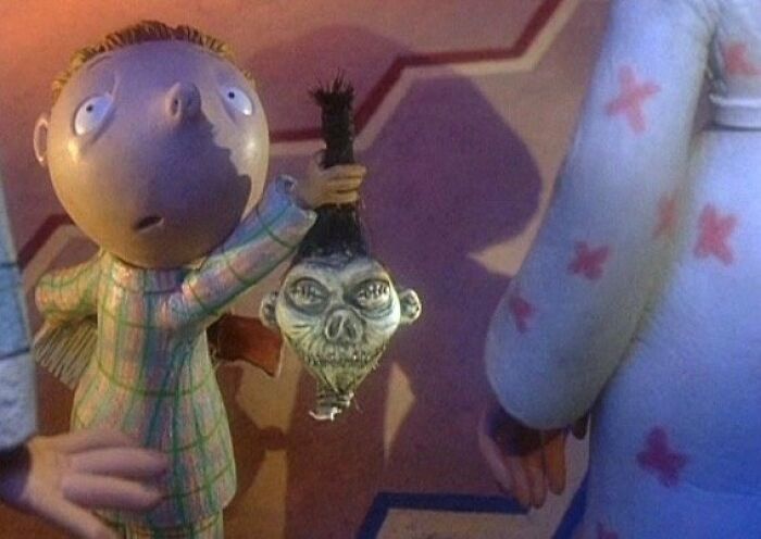 Animated child holding a bizarre Christmas gift with a surprised expression.