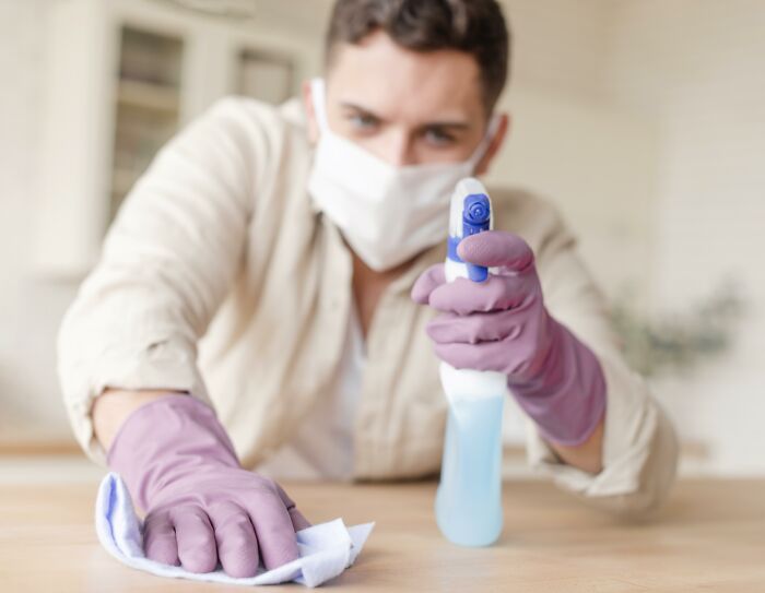 Person in gloves and mask cleaning surface with spray, illustrating everyday things that might seem harmless.
