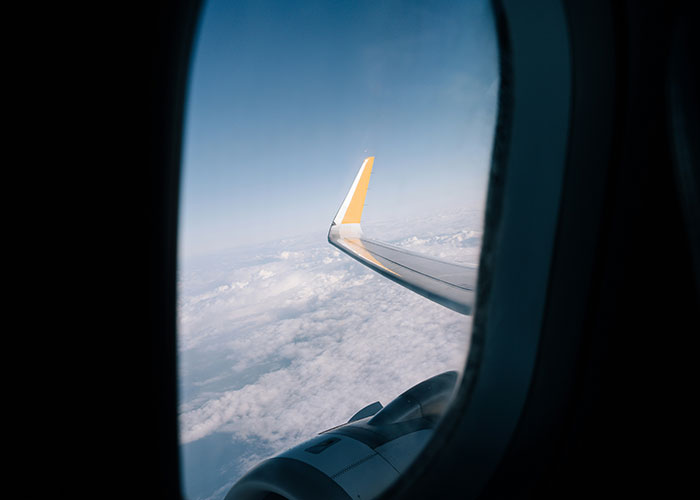 View from an airplane window showing a wing above the clouds, symbolizing travel choices and seat preferences. View from an airplane window showing a wing above the clouds, symbolizing travel choices and seat preferences.