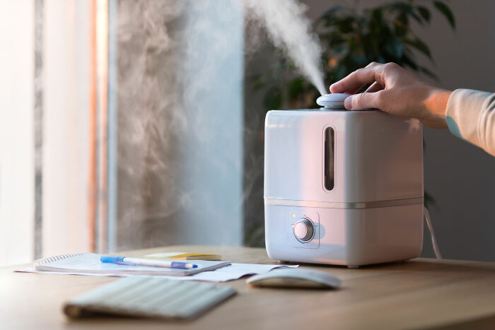 Humidifier on a desk with a hand adjusting settings, highlighted as a money-saving purchase.