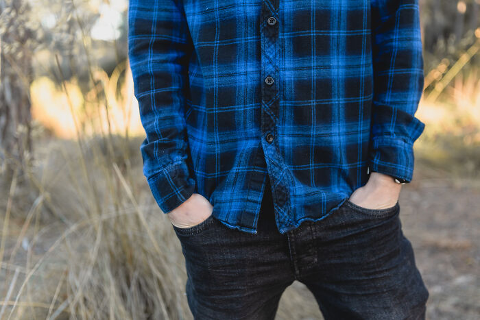 Person in a blue plaid shirt with hands in pockets.