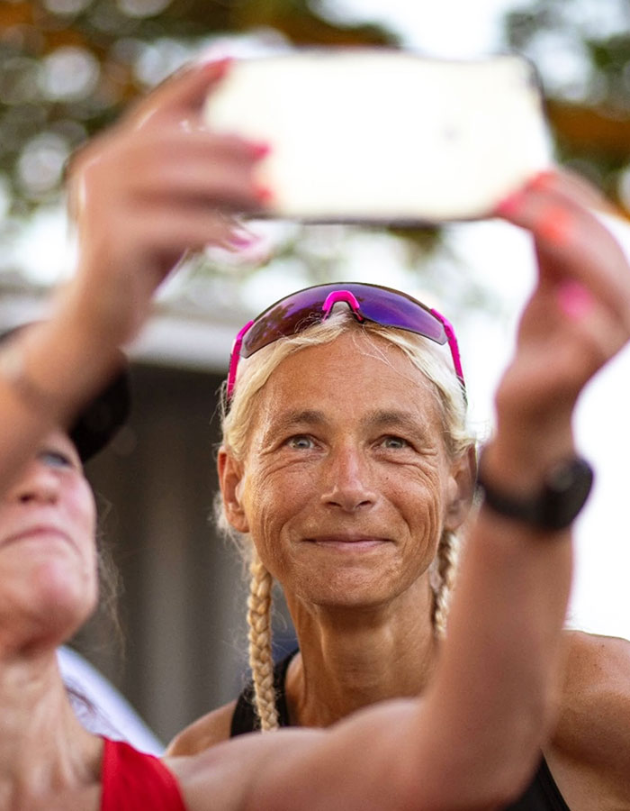 55-year-old woman smiling while taking a selfie, wearing sporty attire after setting a record for marathons in a year. 55-year-old woman smiling while taking a selfie, wearing sporty attire after setting a record for marathons in a year.