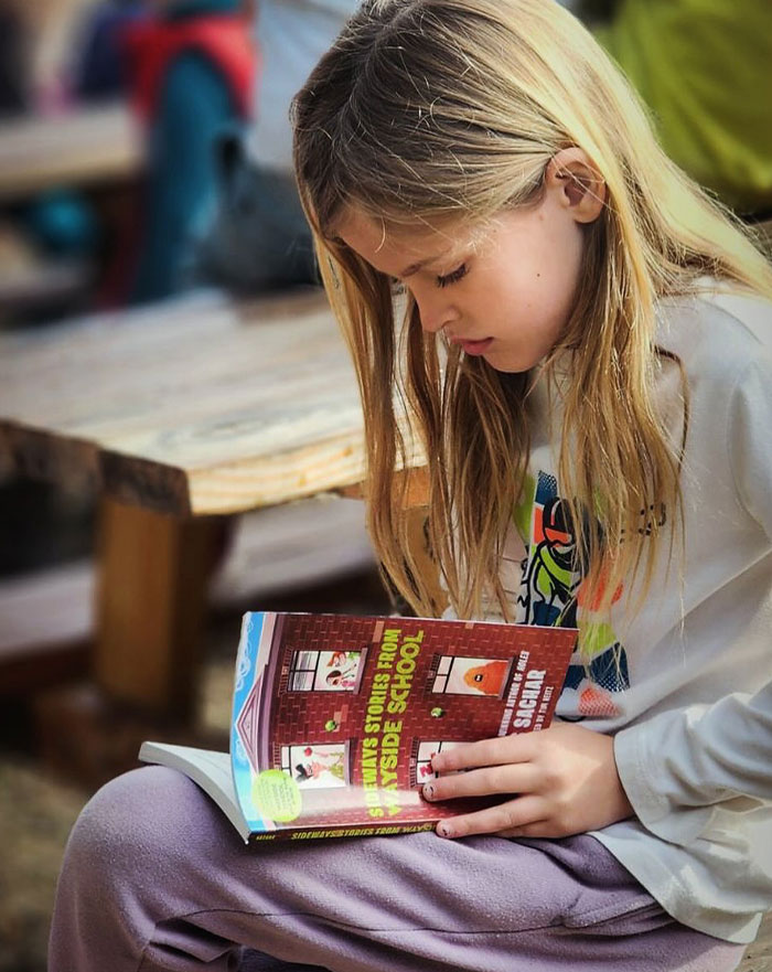 Journey River Green reading a book intently on a bench, representing Megan Fox kids and co-parenting themes.