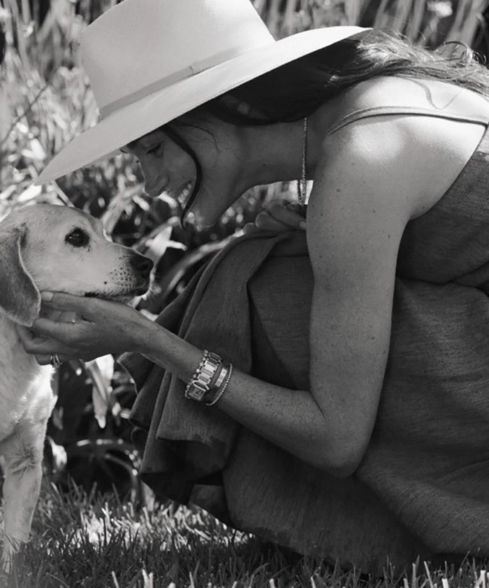 Celebrity smiling at a dog in a garden, wearing a hat, during La wildfires. Celebrity smiling at a dog in a garden, wearing a hat, during La wildfires.