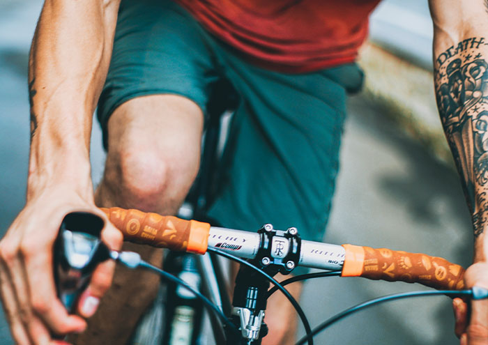 Man with tattoo riding a bicycle, showcasing a casual outdoor setting.