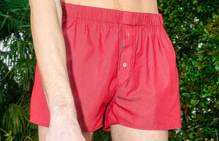 Man in red shorts standing in a garden, addressing sensitive questions.