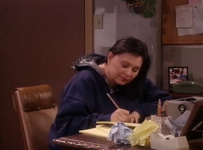 "Person writing at a cluttered desk, symbolizing TV show disappointment among fans."