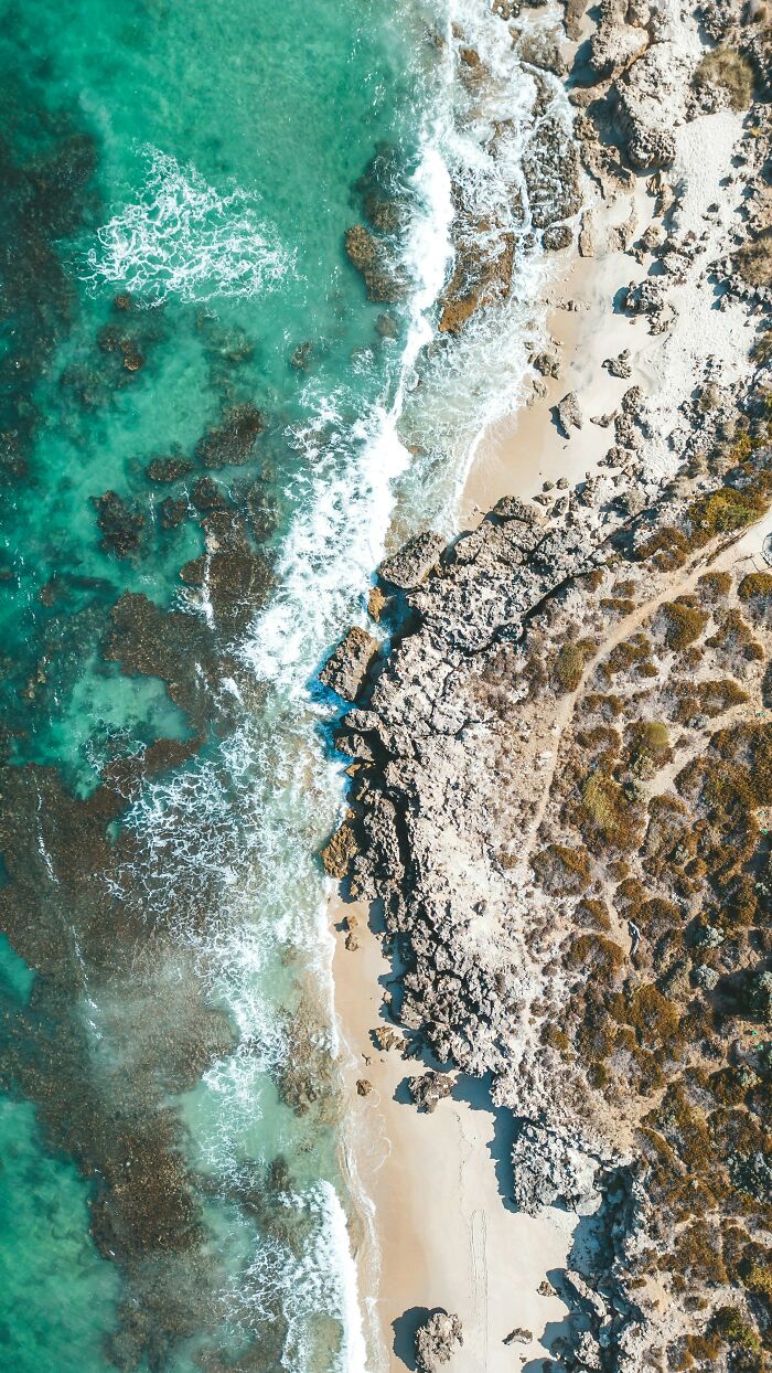 Aerial view of a stunning beach with turquoise waves and rocky shoreline, showcasing incredible world photos.