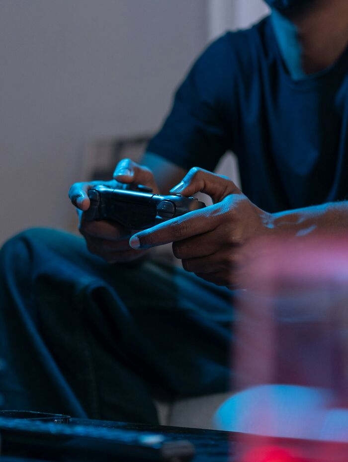 Teen playing video games indoors, holding a controller, highlighting parents' infuriating actions affecting teen relationships.