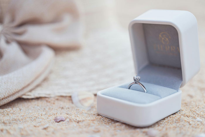 A family heirloom ring in an open box resting on sandy beach. A family heirloom ring in an open box resting on sandy beach.