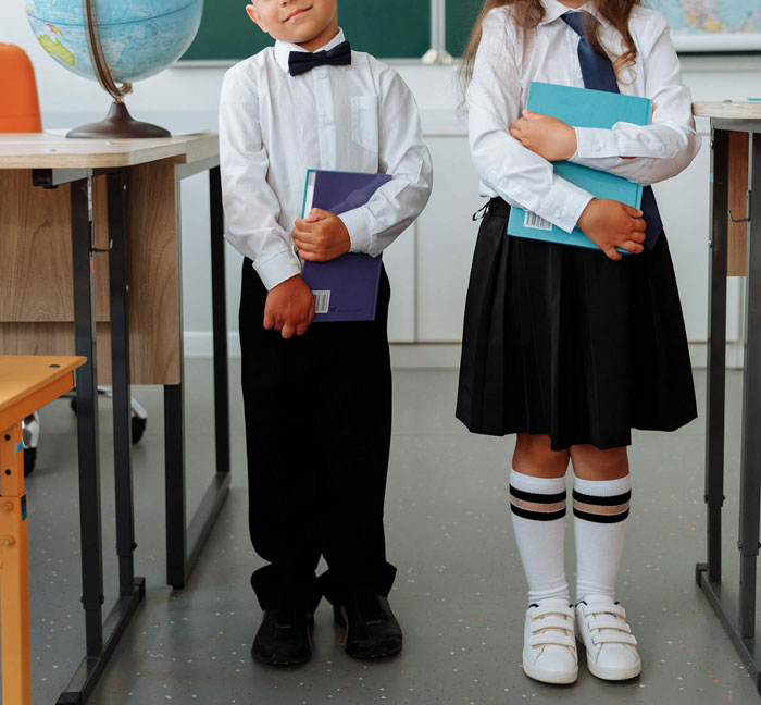 Children in school uniforms standing in a classroom, reflecting a dress code compliance theme. Children in school uniforms standing in a classroom, reflecting a dress code compliance theme.