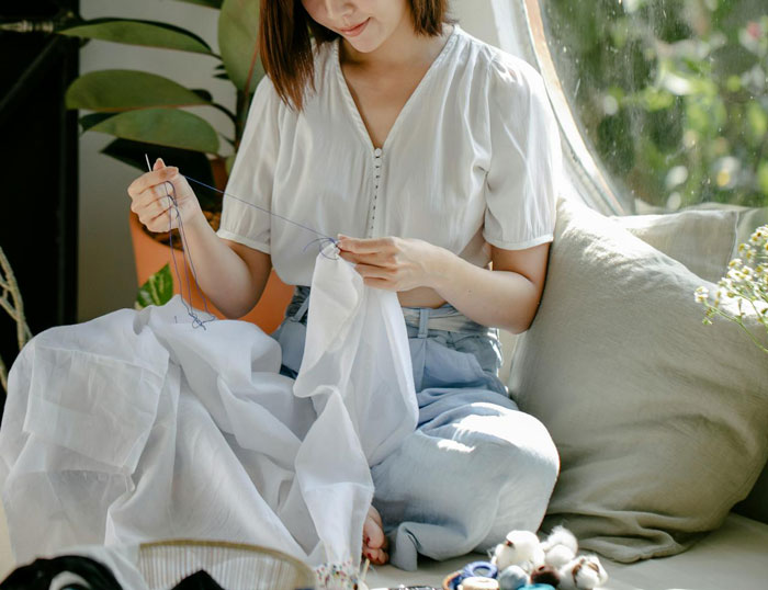A mom sewing a dress, demonstrating school dress code loophole compliance, sitting in a sunlit room. A mom sewing a dress, demonstrating school dress code loophole compliance, sitting in a sunlit room.