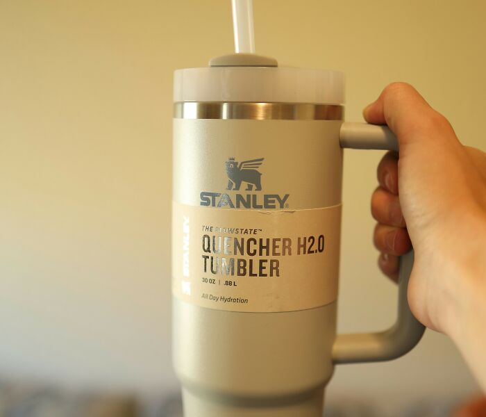 A hand holding a Stanley Quencher H2.0 tumbler, representing trends some choose not to follow.
