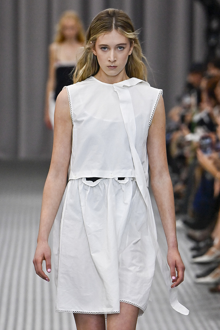 Sunday Rose in a white dress on the runway, showcasing the latest fashion trend.