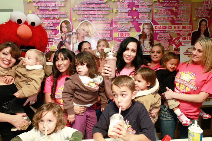 Nadya Suleman in a milkshake shop with her children and others, holding a milkshake and smiling. Nadya Suleman in a milkshake shop with her children and others, holding a milkshake and smiling.
