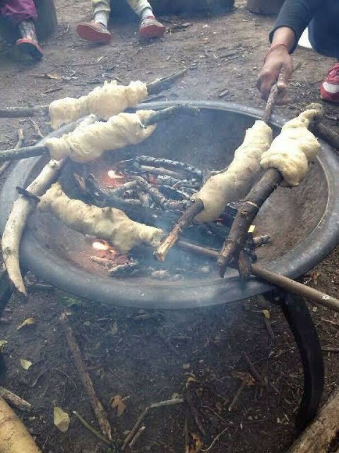 Old-school campfire cooking with dough wrapped on sticks, evoking childhood memories.