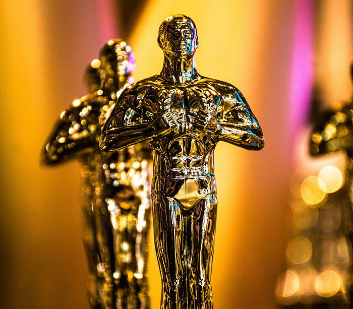 Oscar statuettes in focus, symbolizing achievement in film industry, highlighting transgender nominee controversy.