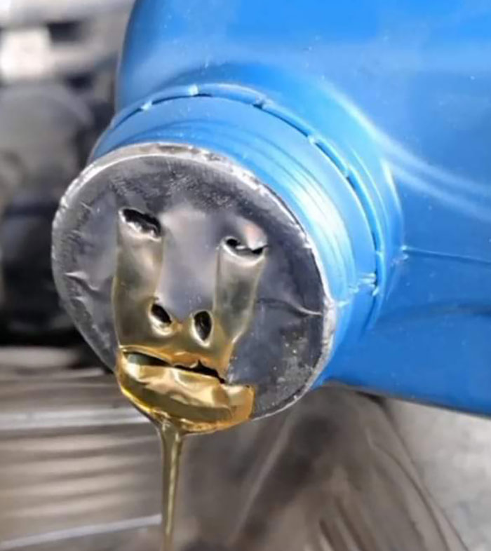 A blue oil can's lid forming a face-like pattern with flowing liquid, showcasing pareidolia.