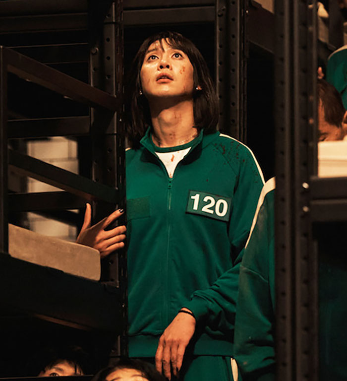 "Squid Game actor in a tense scene, wearing a green tracksuit with number 120. "Squid Game actor in a tense scene, wearing a green tracksuit with number 120.
