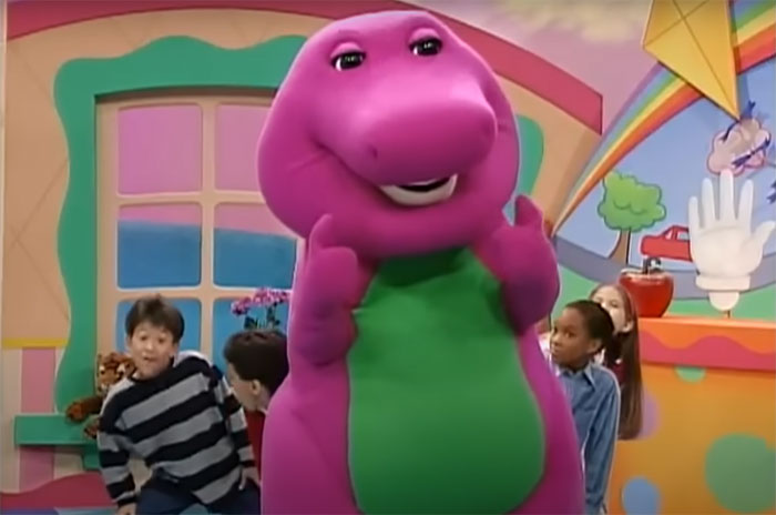 Children play with a life-sized dinosaur in a colorful room setting.