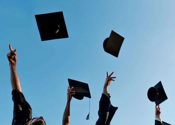 Graduation caps thrown into the sky, celebrating high school achievements.