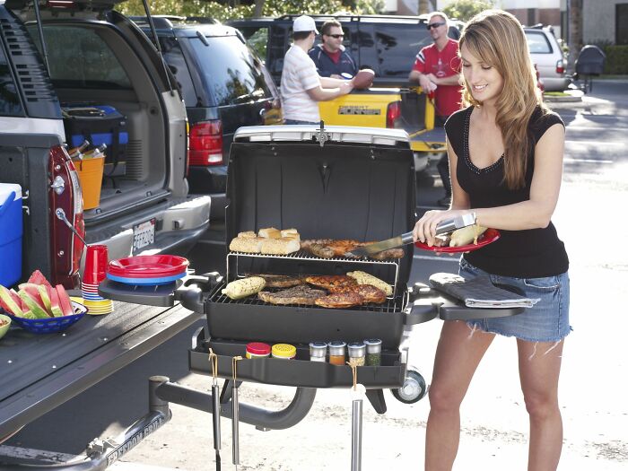 A woman grilling food at a tailgate party, a peculiar tradition normal in some countries.