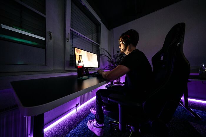 Person gaming at night with neon lights, wearing headphones, despite struggling to grasp certain concepts.