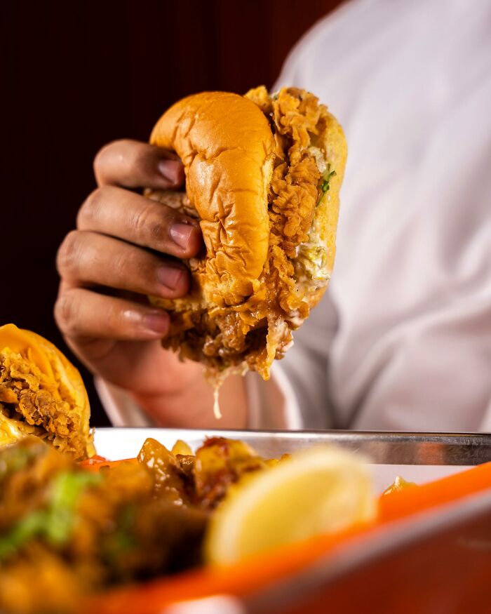 Person holding a fried chicken sandwich, experiencing a lifetime supply win.