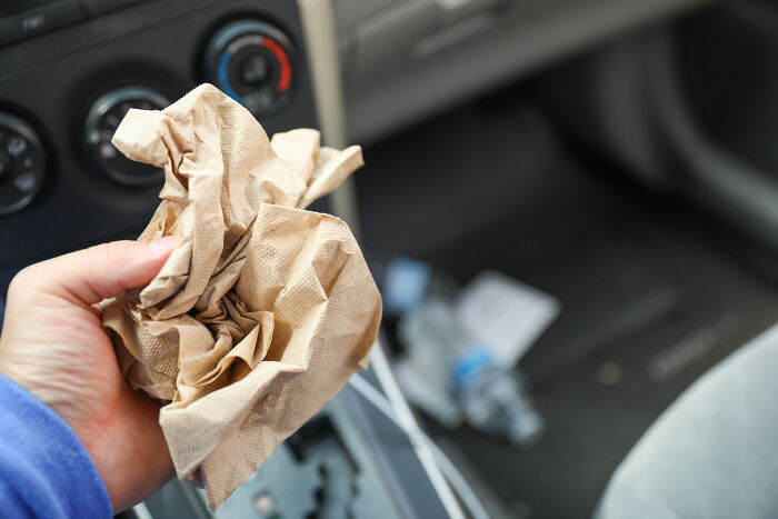 Hand holding paper towels in a car interior, symbolizing affordable ways to make life easier.