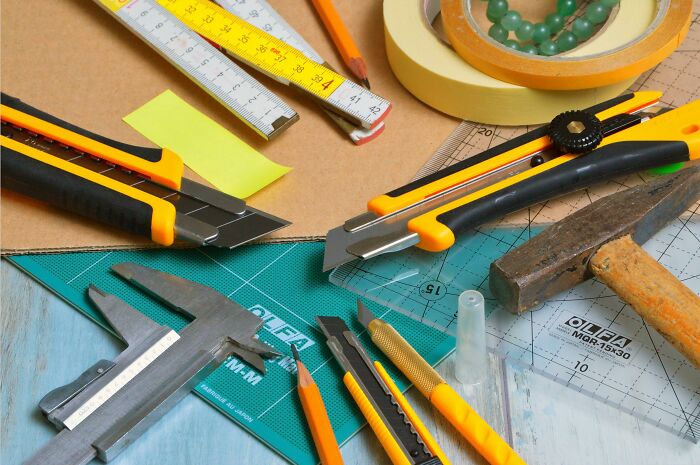 Affordable tools on a desk including cutters, measuring tape, hammer, and a ruler for easier crafting and DIY projects.