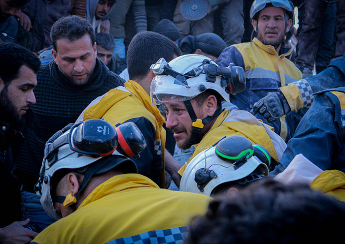 Rescue workers in safety gear at earthquake disaster site.