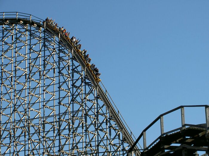 Roller coaster ascending, symbolizing overlooked historical events, under a clear blue sky.