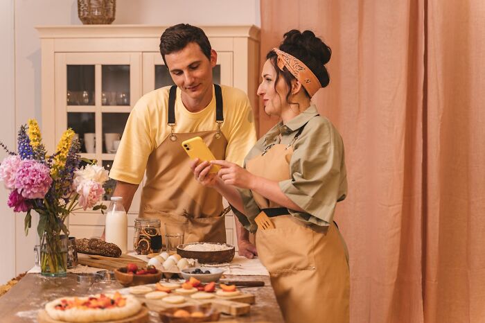 Couple in a kitchen discussing recipes, surrounded by ingredients, highlighting reasons for significant weight gain.