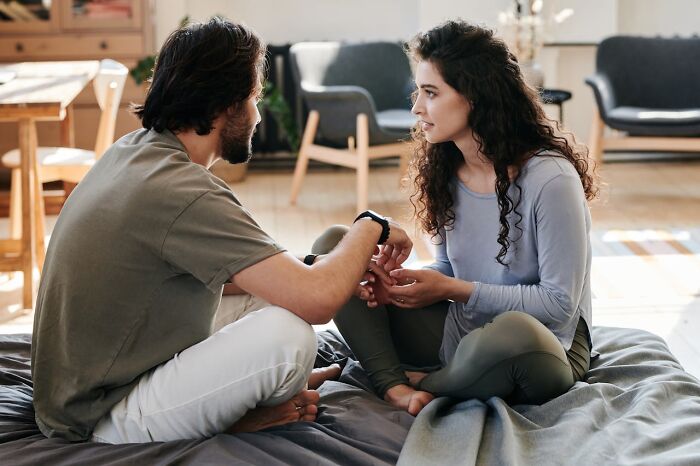 Man and woman sitting on a bed in conversation, focusing on connection and understanding, highlighting non-s****l attraction.