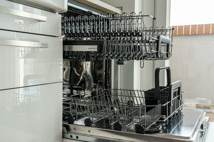 Open dishwasher with racks extended, showcasing a space-saving kitchen appliance.