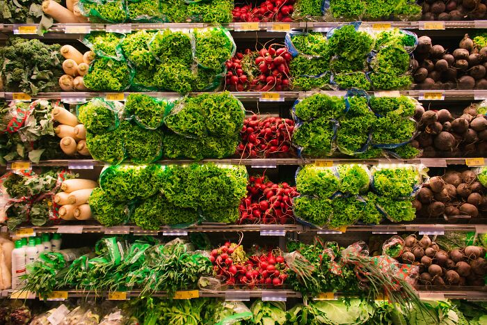 Grocery store produce aisle showcasing fresh greens and vegetables, representing smart budget-friendly shopping choices.