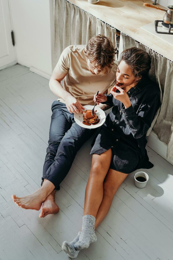 Couple sitting on the floor eating pancakes, highlighting reasons for significant weight gain.