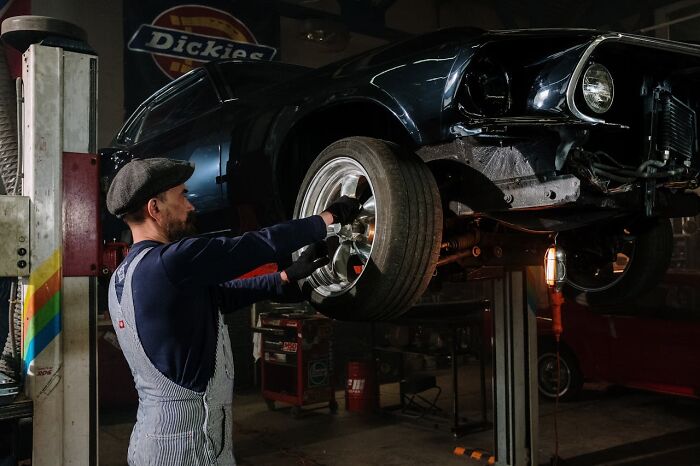 Mechanic working on a car in a garage, showcasing non-s****l skills that can be attractive to women.