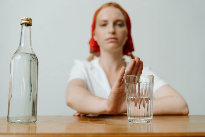 Woman gesturing refusal towards a glass of water, highlighting seemingly harmless everyday dangers.