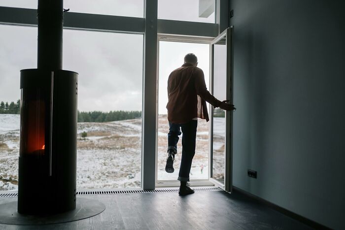 Person stepping outside, showing consequences of cheating partner with snow-covered landscape in the background.