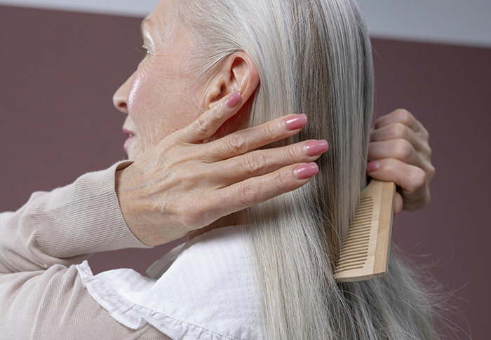 Older woman combing her long gray hair.