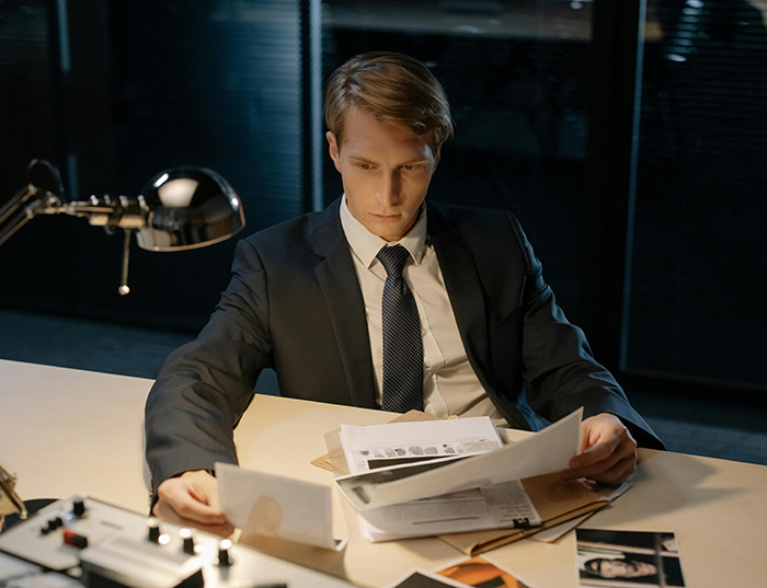 Man in suit examining documents at a desk.