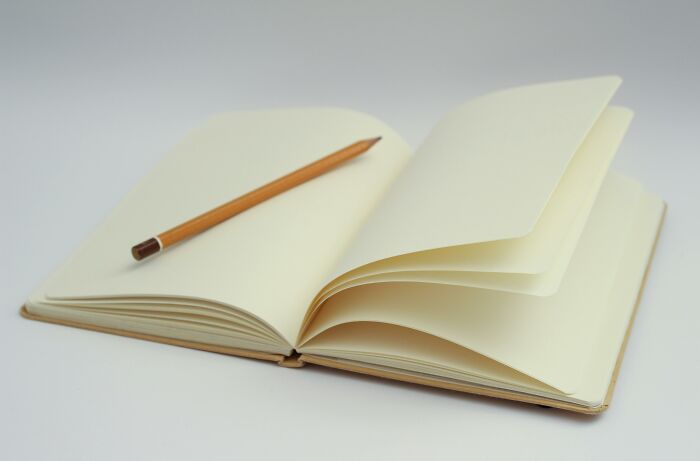 Open notebook with a pencil, representing backstories and brand beginnings. Open notebook with a pencil, representing backstories and brand beginnings.