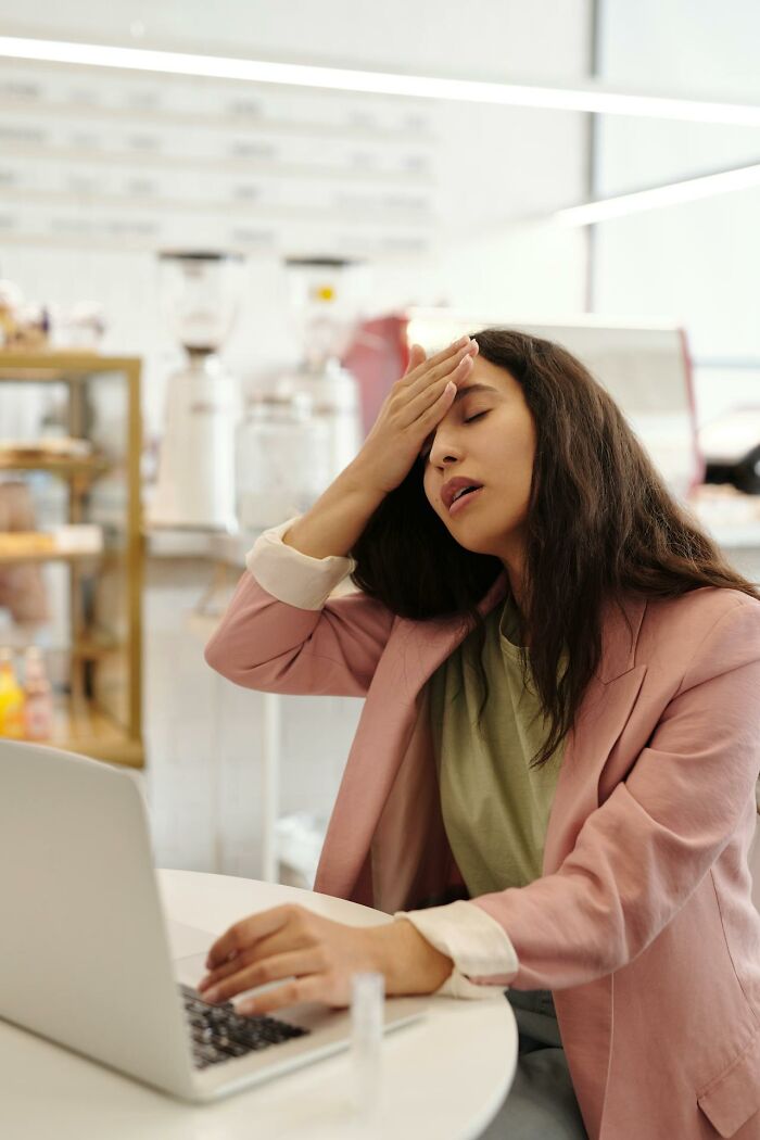 A tired woman in a cafe with a laptop, representing reasons for significant weight gain.