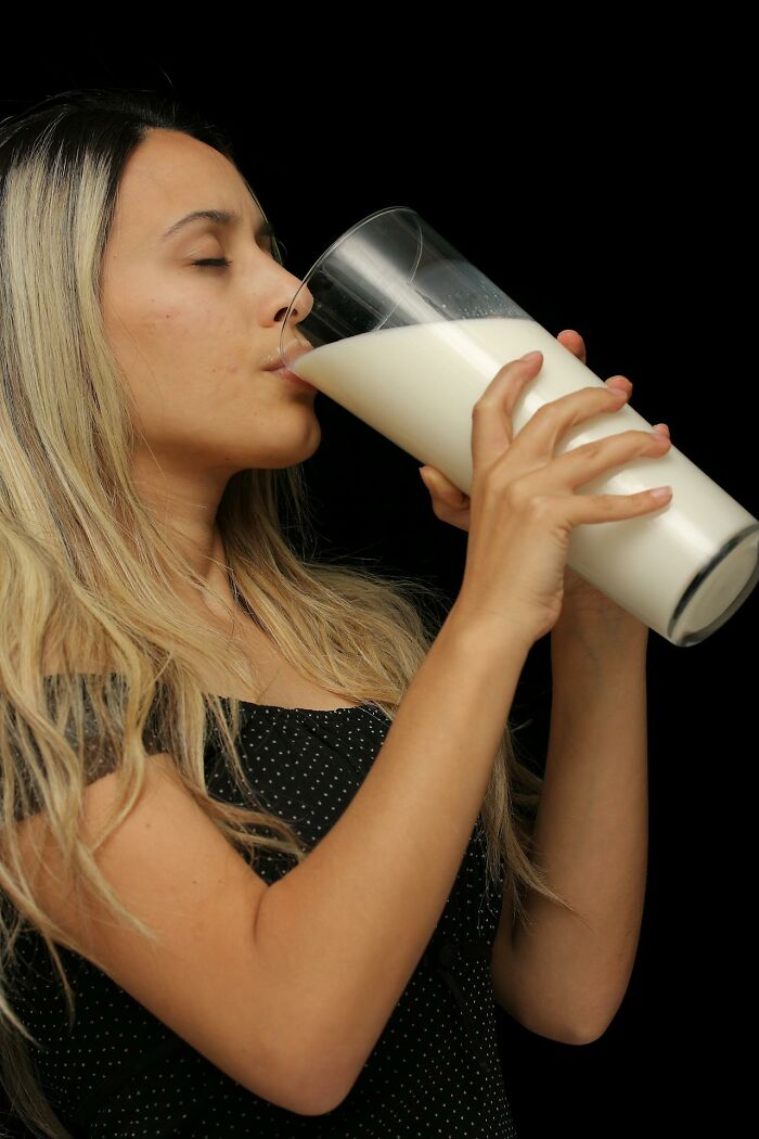 Woman drinking from a large glass of milk, highlighting reasons for weight gain.